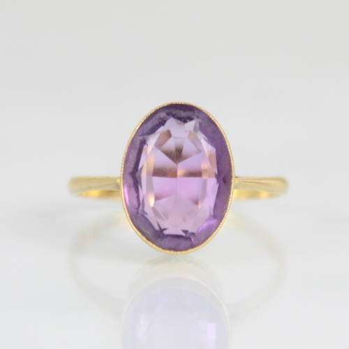 171 - An early 20th century untested amethyst ring, the oval cut amethyst within yellow metal milgrain set... 