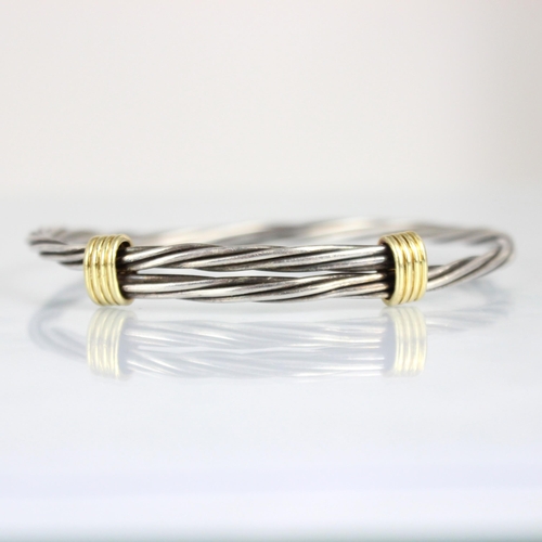 179 - A Tiffany and Co 18ct and silver bangle, the white metal rope twist bangle with twin yellow metal sp... 