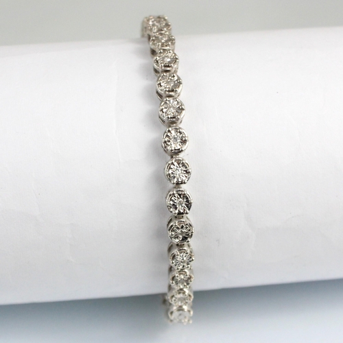 180 - A diamond line bracelet, the thirty seven round cut diamonds within white metal illusion setting edg... 