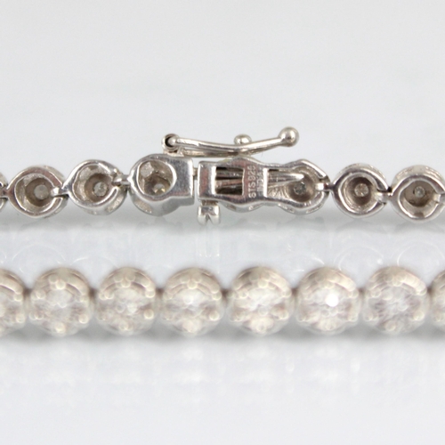 180 - A diamond line bracelet, the thirty seven round cut diamonds within white metal illusion setting edg... 