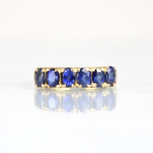 193 - A yellow metal synthetic sapphire six stone ring, the six oval cut synthetic sapphires within claw s... 