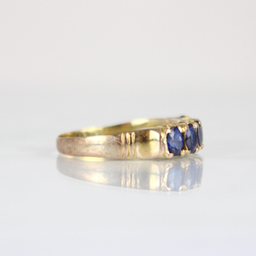 193 - A yellow metal synthetic sapphire six stone ring, the six oval cut synthetic sapphires within claw s... 