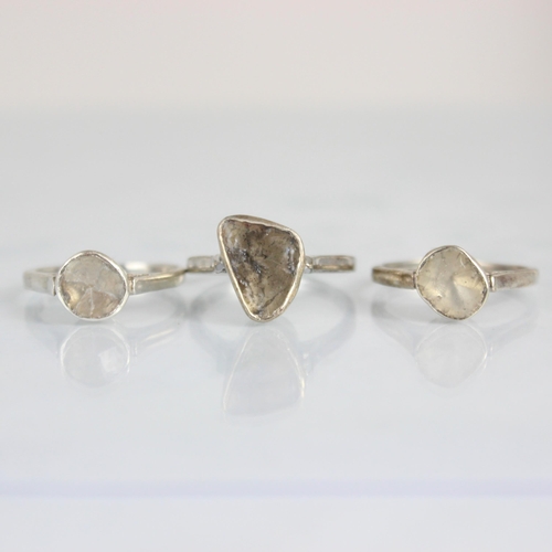 196 - A group of three polki cut diamond rings, all three rings of organic form in silver coloured rub ove... 