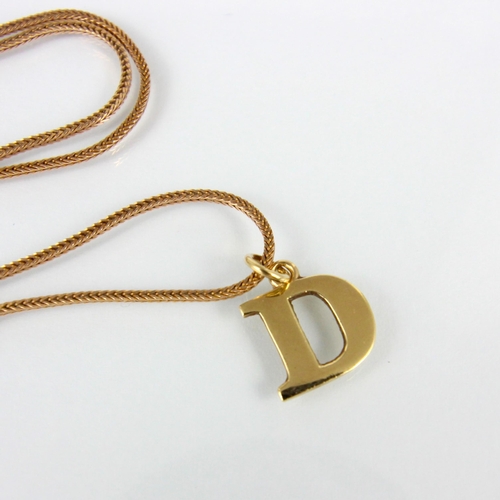 206 - A 9ct ‘D’ initial pendant, the plain polished pendant stamped to reverse, 2cm long, upon an associat... 