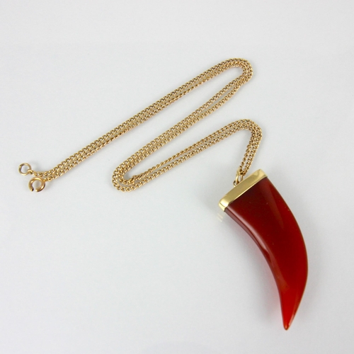 220 - A yellow metal mounted carnelian pendant, designed as a claw with plain polished mount and indistinc... 