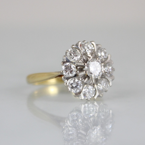 232 - An Edwardian style diamond cluster ring, the raised central round cut diamond within surround of eig... 