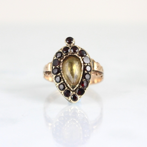 241 - An early 19th century foil backed garnet ring, the central pear cut pale yellow stone encompassed by... 