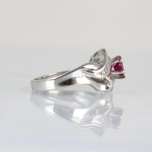 259 - A ruby and diamond stylised cluster ring, the central raised round cut ruby within baguette cut diam... 