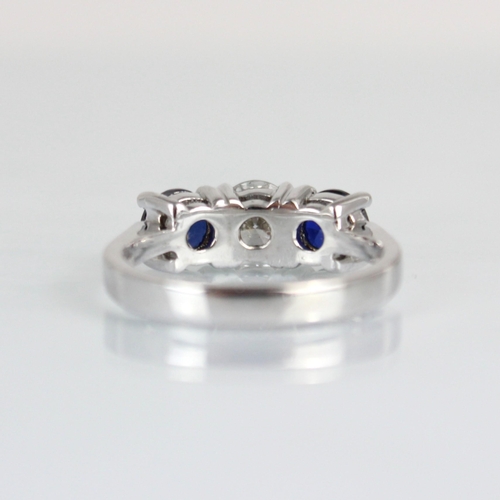 263 - A bespoke sapphire and diamond three stone ring, the central round cut diamond with smaller round cu... 