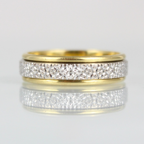 264 - A two tone yellow metal spinning ring, the central strip of white metal with engraved detail, within... 