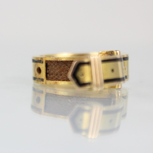 274 - A 19th century enamel mourning ring, formed as buckle with black enamel border, hinged to reveal pla... 