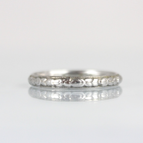 284 - An early 20th century white metal wedding band, engraved with continuous floral design, ring size L,... 