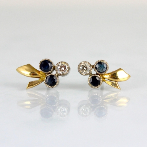 286 - A pair of diamond and untested sapphire stud earrings, of trefoil stylised floral design, within mil... 