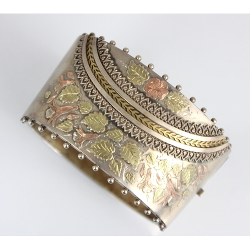 293 - A Victorian white metal bangle, the tapered bangle with gilt metal floral decoration, 6.5cm at wides... 