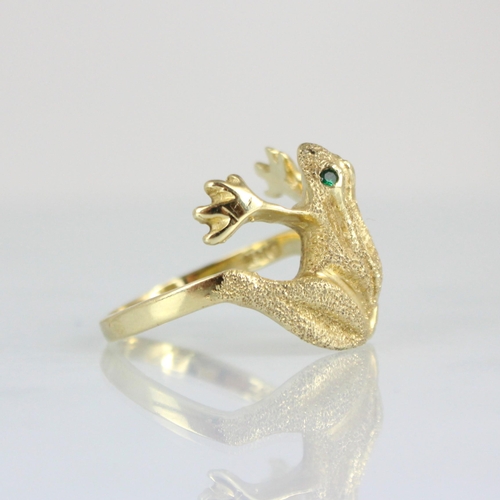 302 - A yellow metal novelty ring, the head designed as a frog with realistically chased detail and green ... 