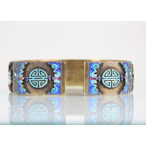 320 - A Chinese enamel and gilt metal bangle, the wide cuff style bangle decorated in naively enamelled sy... 