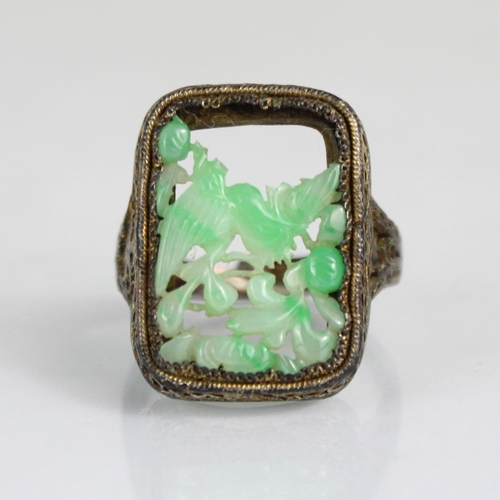 322 - An early 20th century jade and paste seed pearl brooch, the oval carved jade panel depicting birds a... 