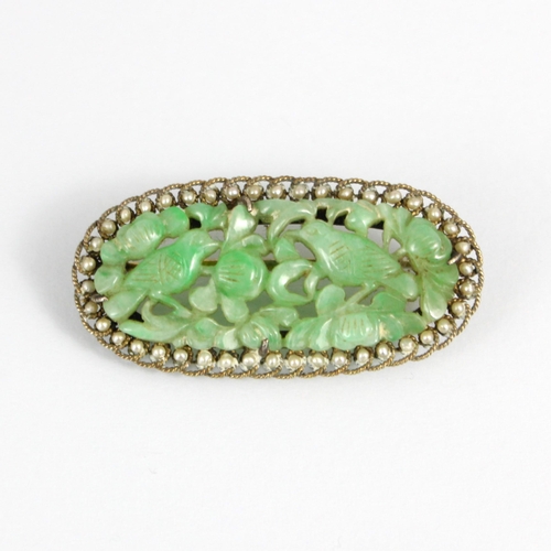 322 - An early 20th century jade and paste seed pearl brooch, the oval carved jade panel depicting birds a... 