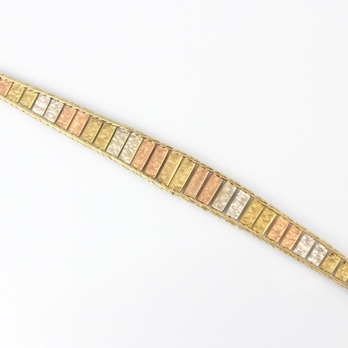 325 - A three tone yellow metal bracelet, the three tone panelled front with textured front, hidden box an... 