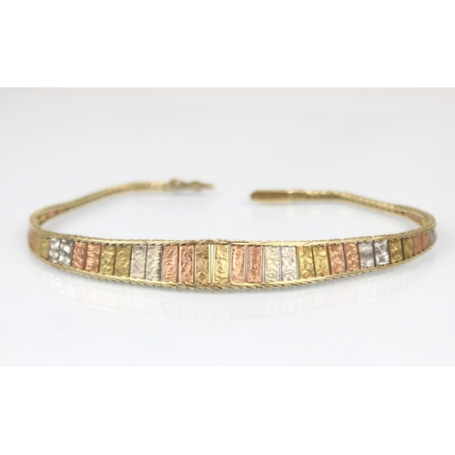 325 - A three tone yellow metal bracelet, the three tone panelled front with textured front, hidden box an... 