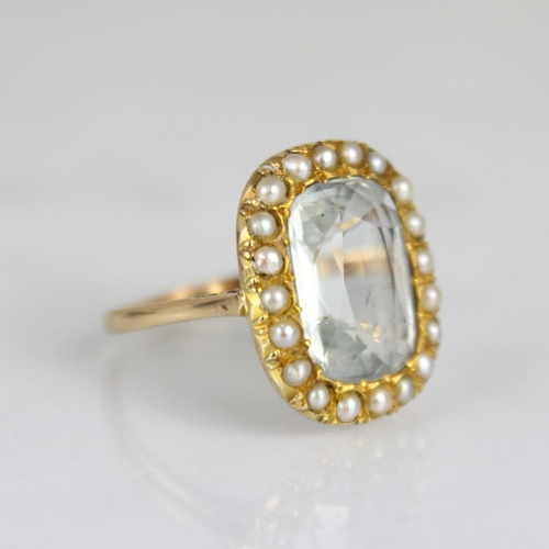 345 - An aquamarine and seed pearl ring, circa 1900, the cushion cut aquamarine within a surround of seed ... 