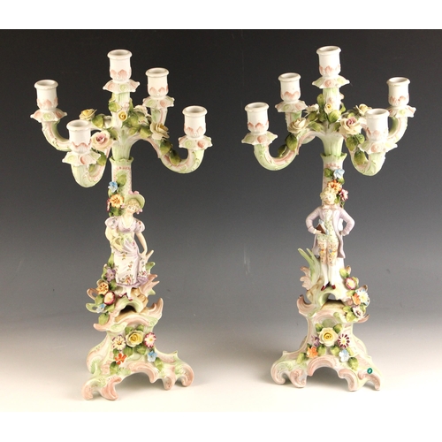 563 - A pair continental porcelain florally encrusted figural candelabra, 19th century, one modelled with ... 