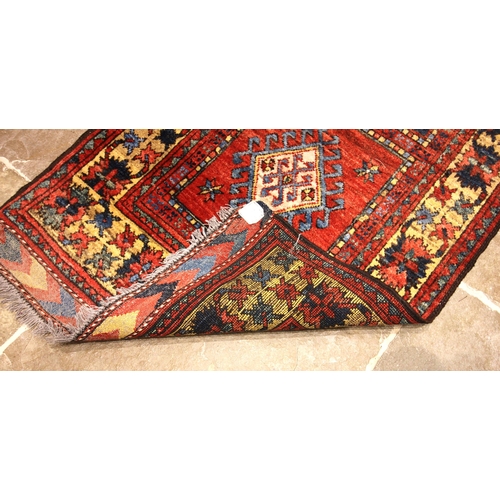 688 - A Pakistan wool runner, in vibrant red, blue and yellow colourways, the central field with five alte... 