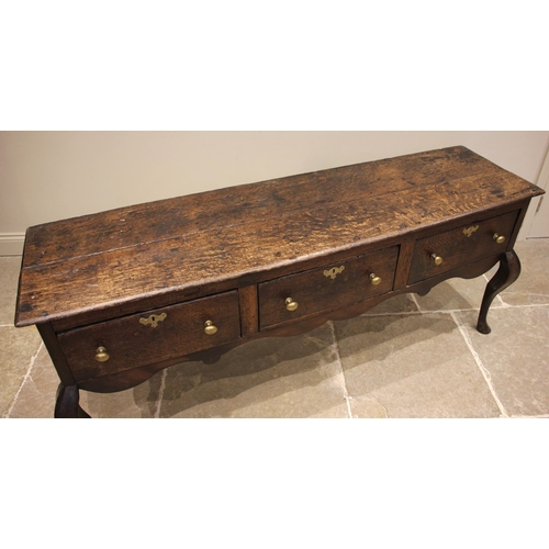 713 - An early 18th century oak Shropshire dresser base, the moulded twin plank top over three pine lined ... 