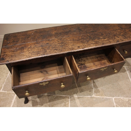 713 - An early 18th century oak Shropshire dresser base, the moulded twin plank top over three pine lined ... 