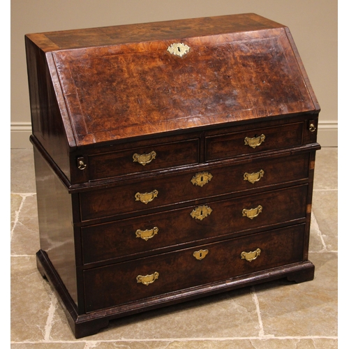 717 - A George II burr walnut and feather banded bureau, the fall front opening to a compartmented interio... 