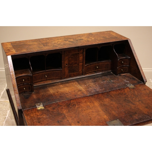 717 - A George II burr walnut and feather banded bureau, the fall front opening to a compartmented interio... 