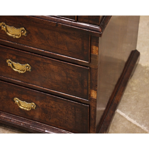 717 - A George II burr walnut and feather banded bureau, the fall front opening to a compartmented interio... 