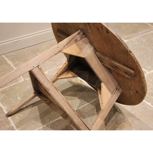 781 - A 19th century stripped oak cricket table, the circular plank top upon chamfered supports united by ... 