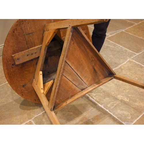 781 - A 19th century stripped oak cricket table, the circular plank top upon chamfered supports united by ... 