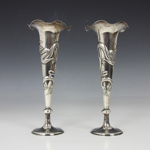 82 - A pair of white metal Chinese posy vases, the shaped rim above tapered stem embossed with dragon dec... 