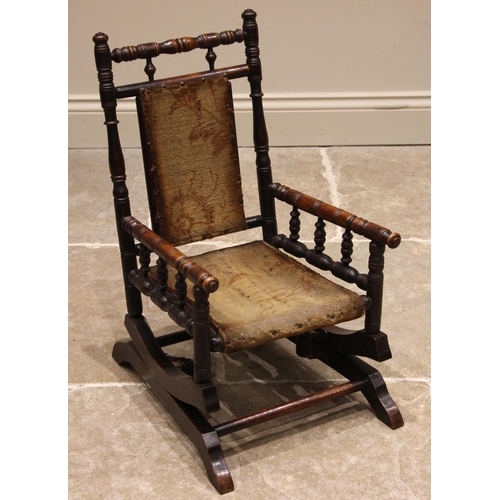 831 - A child's stained walnut American rocker, early 20th century, the turned frame mounted upon coiled s... 