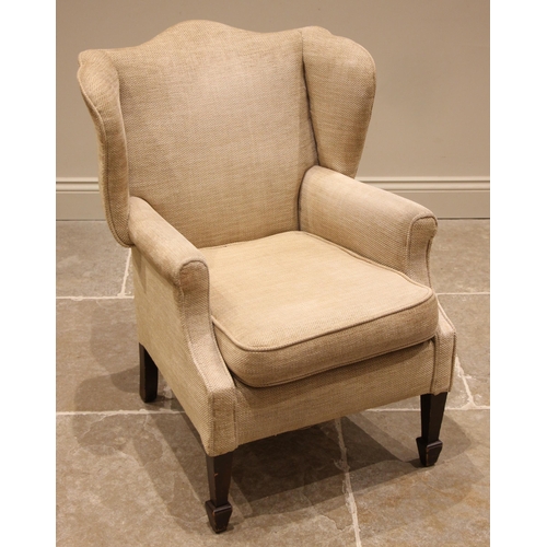 842 - A wing back armchair, 20th century, of cottage proportions, re-covered in oatmeal fabric, upon taper... 