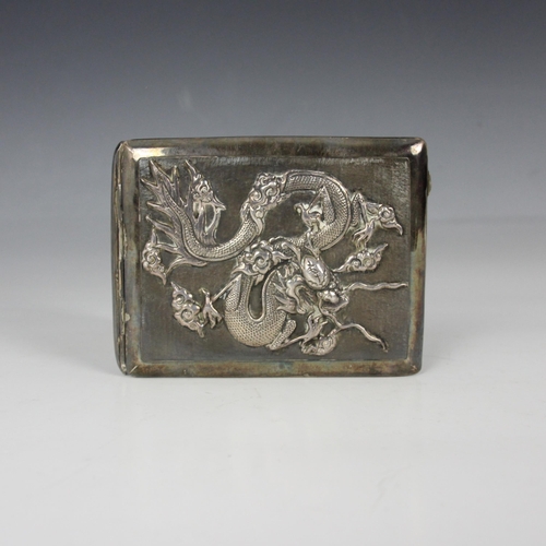 94 - A Chinese white metal cigarette case, of rectangular form with cast dragon detail to the front, cart... 