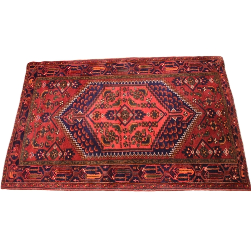 689 - A Caucasian hand knotted wool rug, in red, blue and green colourways, the central vibrant red lozeng... 