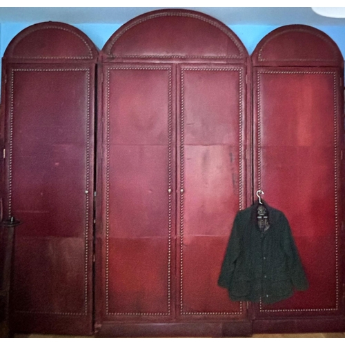 823 - An impressive and large red leather wardrobe, mid 20th century, of triple arched form, the pair of c... 