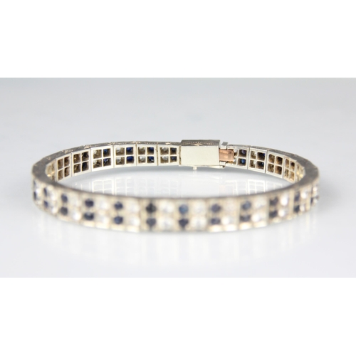 166 - An Art Deco style white and blue sapphire bracelet, the graduated white metal square panel set with ... 