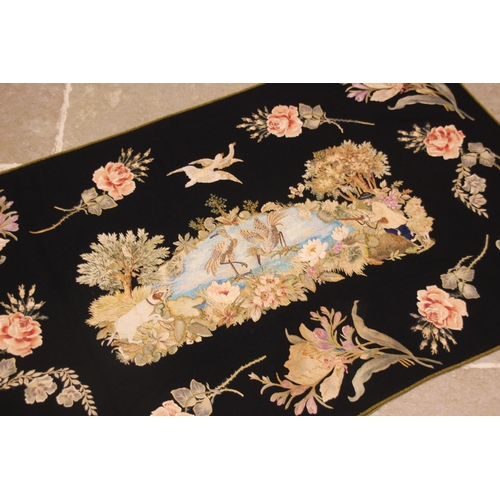 606 - A black felt and long stitch silk embroidered wall hanging, 19th century, possibly French, the centr... 