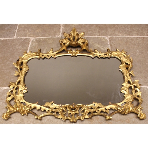 663 - A French giltwood and gesso rococo wall mirror, 19th century, the 'C' scroll openwork leafy crest ex... 