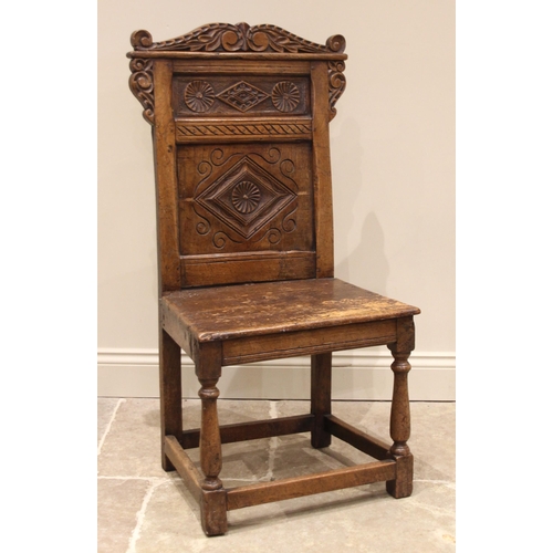 718 - A 17th century oak side chair, the carved scroll pediment over a back panel detailed with roundels a... 