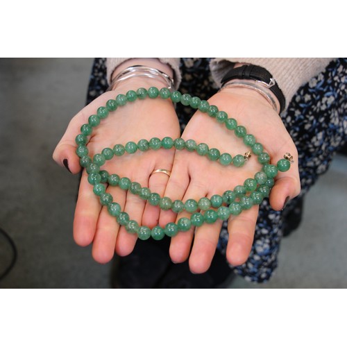 291 - A string of hydrogrossular garnet beads, the ‘jade’ coloured beads with screw barrel fastening, 76cm... 