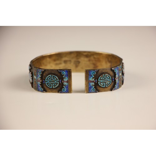 320 - A Chinese enamel and gilt metal bangle, the wide cuff style bangle decorated in naively enamelled sy... 