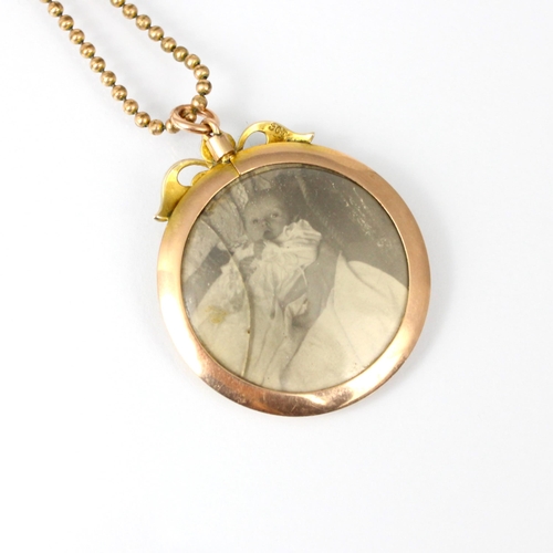 191 - An early 20th century yellow metal pendant, the plain polished circular pendant surmounted with seed... 