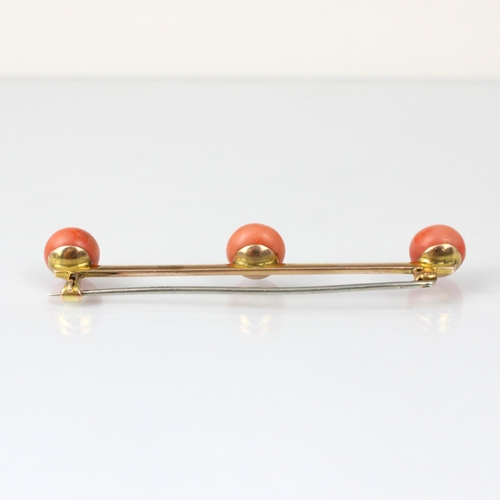 238 - A 20th century coral bar brooch, the three spherical coral upon yellow metal knife edge bar brooch, ... 