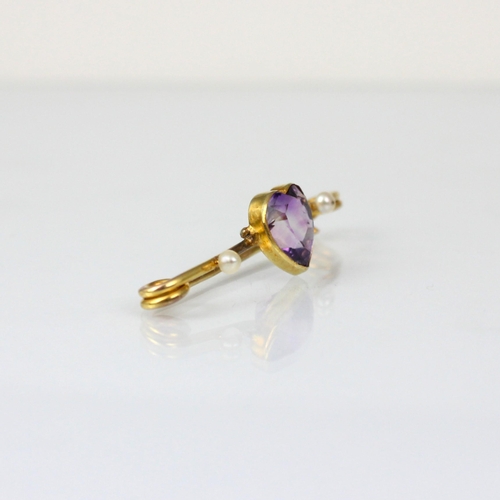 239 - An early 20th century amethyst bar brooch, the central heart shaped amethyst within yellow metal rub... 