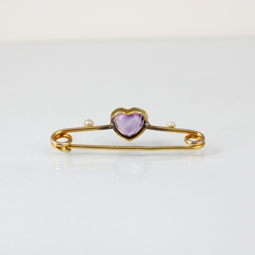 239 - An early 20th century amethyst bar brooch, the central heart shaped amethyst within yellow metal rub... 